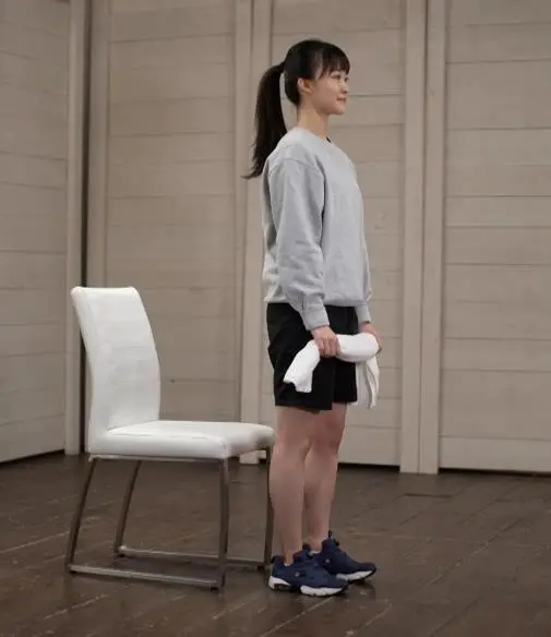 椅子静蹲起始姿势:双手握住毛巾,站在椅子前,双脚打开到与肩同宽